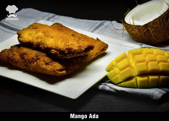 A close-up of mango ada from Ikkayees: soft steamed rice-flour dumplings filled with sweet mango and coconut, wrapped in vibrant banana leaf-Kerala cuisine unique